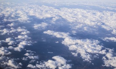 Bulutlar ve açık mavi gökyüzü ve Dünya'dan yükseklik bir uçak penceresinde görüntüleyin. Hava dağların güzel görünümünden. 