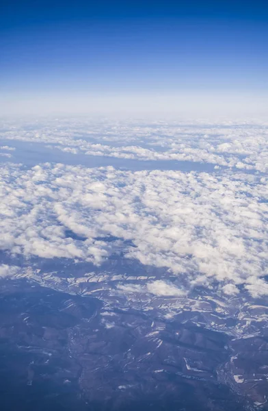 从平面窗口可以看到云和蓝色晴朗的天空, 从高处看地球。从山的空气美丽的看法. — 图库照片