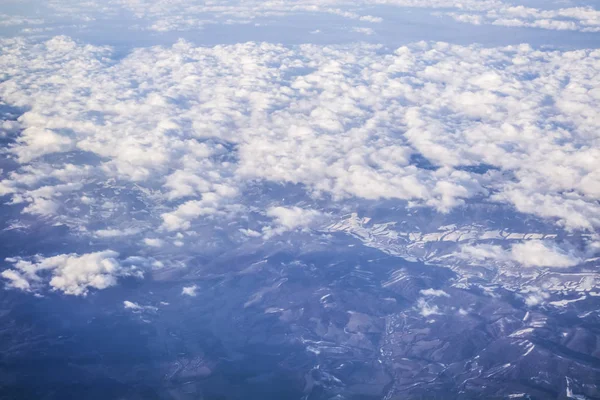 从平面窗口可以看到云和蓝色晴朗的天空, 从高处看地球。从山的空气美丽的看法. — 图库照片