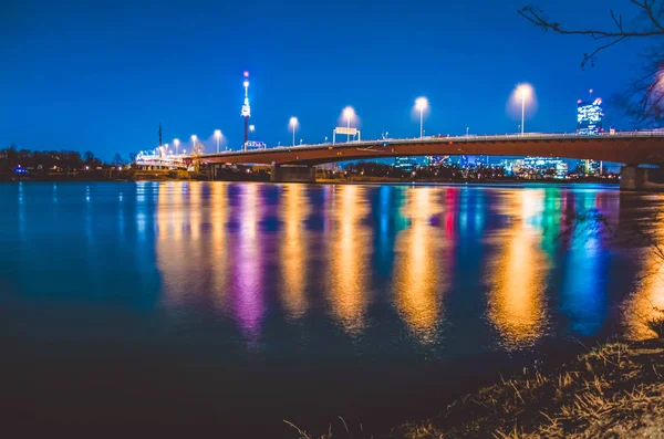 Kvällen flerfärgad avfyrar av moderna skyskrapor och bron i Wien återspeglas i floden. Vacker utsikt. Landskap — Stockfoto