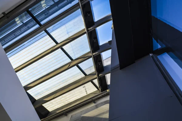 Modern buildings of unusual forms from glass and metal. Geometry of lines and curves. The inclined facade. Blue sky.