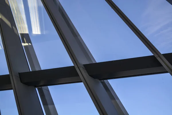 Edificios modernos de formas inusuales de vidrio y metal. Geometría de líneas y curvas. La fachada inclinada. Cielo azul . — Foto de Stock