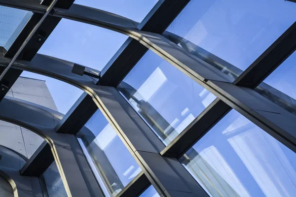 Edificios modernos de formas inusuales de vidrio y metal. Geometría de líneas y curvas. La fachada inclinada. Cielo azul . — Foto de Stock