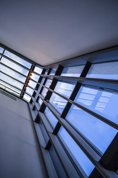 Edificios modernos de formas inusuales de vidrio y metal. Geometría de líneas y curvas. La fachada inclinada. Cielo azul . — Foto de Stock