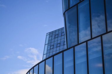 Ofis binaları modern mimarisi. Cam ve metal bir eğri dalga şeklinde bir gökdelen. Mavi gökyüzü ve evleri Windows yansımaları. İş Merkezi.