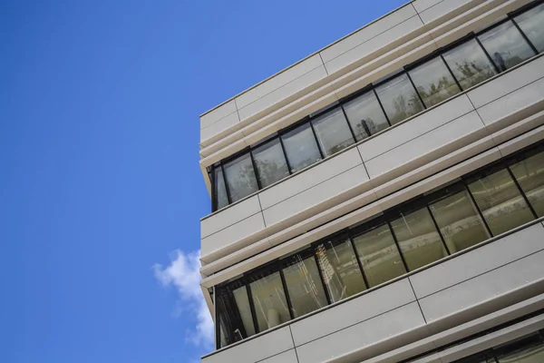 Edificios modernos de formas inusuales de vidrio y metal. Geometría de líneas y curvas. La fachada inclinada. Cielo azul . — Foto de Stock