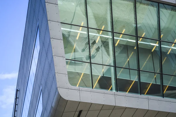 Modern buildings of unusual forms from glass and metal. Geometry of lines and curves. The inclined facade. Blue sky.