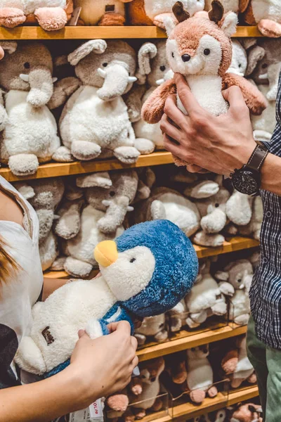 Joven pareja amorosa en la tienda elegir los niños juguetes blandos en un regalo. Compras en el centro comercial. Emociones. Familia . —  Fotos de Stock