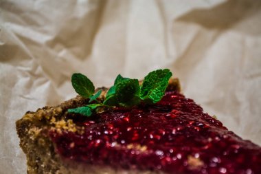 Taze bir parça kek ahududu Kraft kağıt üzerinde bir nane şubesi ile gelen reçelli. Kahve Dükkanı. Ev yapımı hamur işleri.