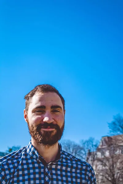 Retrato jovem barbudo cara com emoções na camisa no fundo do céu azul claro no parque. Moda de rua, hipster . — Fotografia de Stock