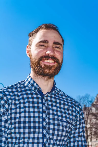 Retrato jovem barbudo cara com emoções na camisa no fundo do céu azul claro no parque. Moda de rua, hipster . — Fotografia de Stock