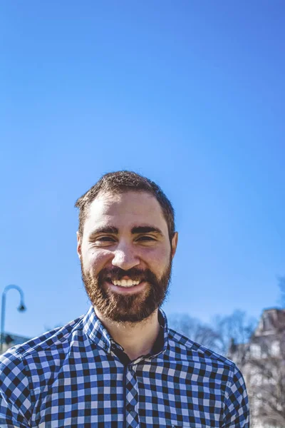 Retrato jovem barbudo cara com emoções na camisa no fundo do céu azul claro no parque. Moda de rua, hipster . — Fotografia de Stock