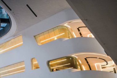 Modern binanın içinde. Eğimli ve yarım daire biçimli duvarlar, büyük pencereler ve balkon, aydınlatma ile. Mimarisi. Geometri.