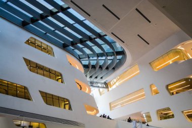 Modern binanın içinde. Eğimli ve yarım daire biçimli duvarlar, büyük pencereler ve balkon, aydınlatma ile. Mimarisi. Geometri.