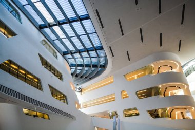 Modern binanın içinde. Eğimli ve yarım daire biçimli duvarlar, büyük pencereler ve balkon, aydınlatma ile. Mimarisi. Geometri.