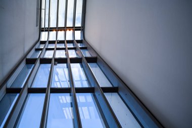 Modern binanın içinde. Eğimli ve yarım daire biçimli duvarlar, büyük pencereler ve balkon, aydınlatma ile. Mimarisi. Geometri.