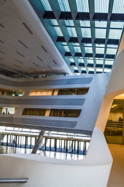 Modern binanın içinde. Eğimli ve yarım daire biçimli duvarlar, büyük pencereler ve balkon, aydınlatma ile. Mimarisi. Geometri.