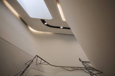 Modern binanın içinde. Eğimli ve yarım daire biçimli duvarlar, büyük pencereler ve balkon, aydınlatma ile. Mimarisi. Geometri.