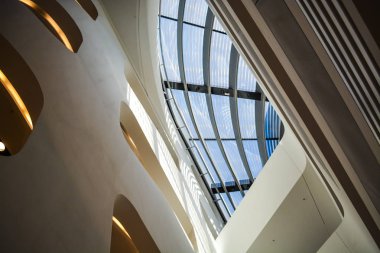 Modern binanın içinde. Eğimli ve yarım daire biçimli duvarlar, büyük pencereler ve balkon, aydınlatma ile. Mimarisi. Geometri.