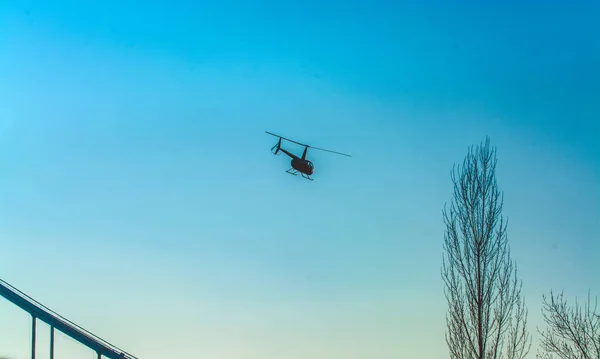 Silhuetten av helikopter i blå klar himmel med solar fläckar av ljus. Varm vårdag. Moderna transporter. — Stockfoto