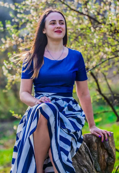 La joven en vestido con falda larga camina en el parque de primavera. La hermosa naturaleza en abril. Clima soleado. Moda . — Foto de Stock