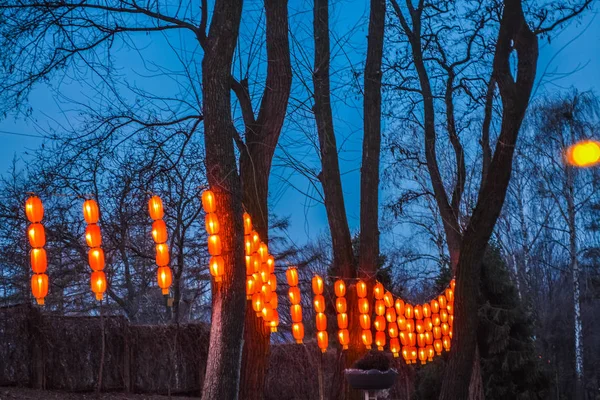 Varias lámparas pequeñas chinas brillantes en el parque. Garland. Una decoración inusual para las calles y la casa. Humor festivo — Foto de Stock