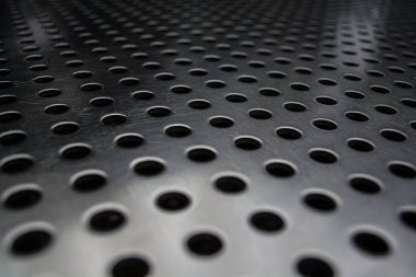 Metal bir plaka delik büyük miktarda gri monofonik arka plan. Yüzey. Doku.