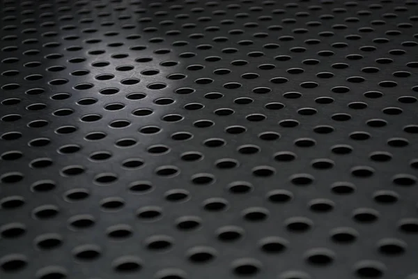 Grauer monophoner Hintergrund mit einer großen Anzahl von Löchern in einer Metallplatte. Oberfläche. Textur. — Stockfoto