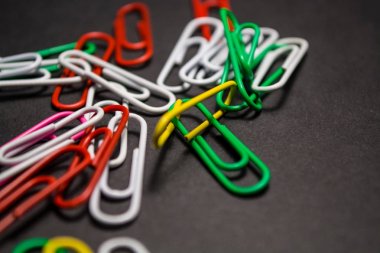 Siyah monofonik arka plan plastik çok renkli ataş yalan vardır. Beyaz, kırmızı, yeşil, sarı renkler. Office.