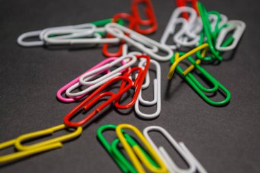 Siyah monofonik arka plan plastik çok renkli ataş yalan vardır. Beyaz, kırmızı, yeşil, sarı renkler. Office.