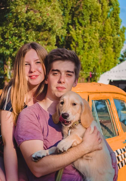 La joven pareja de enamorados casados pasea con el perrito en el parque. Golden retriever . —  Fotos de Stock