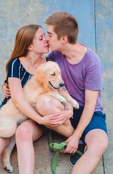 La giovane coppia amorevole sposata passeggia con il cagnolino nel parco. Recupero d'oro . — Foto Stock