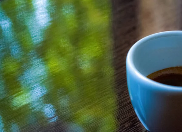 Weiße Keramiktasse aus Espresso auf glänzend brauner Oberfläche. Kaffee und guten Morgen. Hintergrund. — Stockfoto