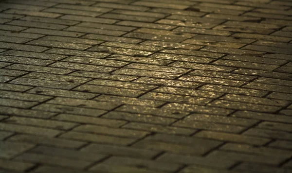 Hintergrund oder Textur von einer gebrochenen und gleichen Fliese mit Lichtflecken und Tropfen. Steinblöcke auf dem Bürgersteig. — Stockfoto