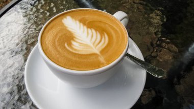 Cam masa üzerinde kapuçino ve latte sanat beyaz fincan. Rosetta. Kahve dükkanı ve sonbahar. Sabah kahvesi.