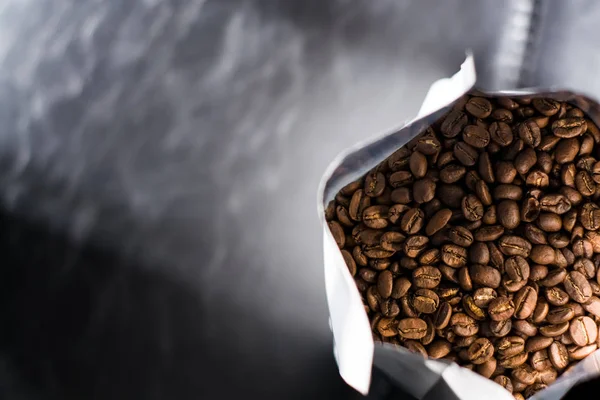 Lots of coffee beans in a bag on dark background. Arabica. Coffee shop.