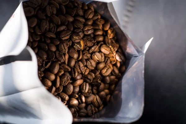 Lots of coffee beans in a bag on dark background. Arabica. Coffee shop.