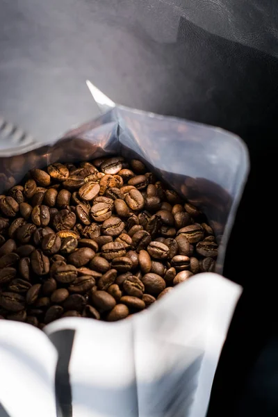 Lots of coffee beans in a bag on dark background. Arabica. Coffee shop.