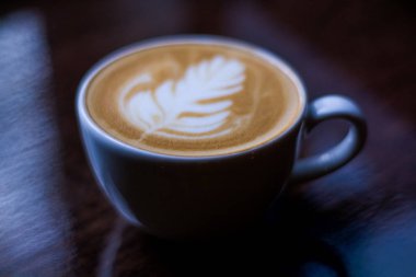 Beyaz rozet desenli fincan Cappuccino. Latte sanatı. Karanlık arka plan. Sabah kahvesi.