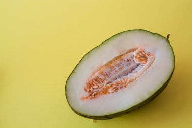 Bir ton yeşil arka plan üzerinde tohumları ile kesilmiş olgun kavun yarısı. Faydalı meyveler. Yaz. Sezon. Vitamin.