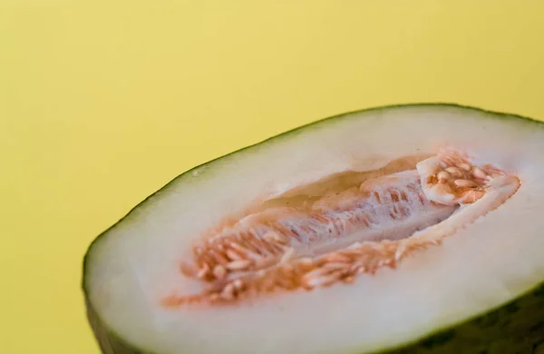 Half of the cut ripe melon with seeds on one-ton green background. Useful fruit. Summer. Season. Vitamins.