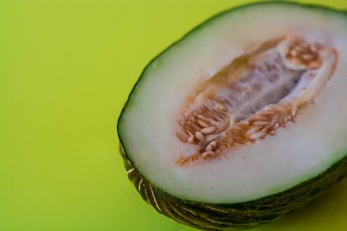 Bir ton yeşil arka plan üzerinde tohumları ile kesilmiş olgun kavun yarısı. Faydalı meyveler. Yaz. Sezon. Vitamin.