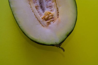 Bir ton yeşil arka plan üzerinde tohumları ile kesilmiş olgun kavun yarısı. Faydalı meyveler. Yaz. Sezon. Vitamin.