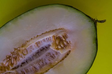 Bir ton yeşil arka plan üzerinde tohumları ile kesilmiş olgun kavun yarısı. Faydalı meyveler. Yaz. Sezon. Vitamin.