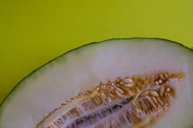 Bir ton yeşil arka plan üzerinde tohumları ile kesilmiş olgun kavun yarısı. Faydalı meyveler. Yaz. Sezon. Vitamin.