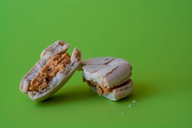 Bir ton yeşil arka plan üzerinde bir kırık makarna zevkle tuzlu karamel. Fransız tatlısı. Tatlı.