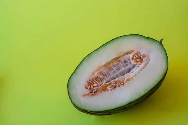 Half of the cut ripe melon with seeds on one-ton green background. Useful fruit. Summer. Season. Vitamins.