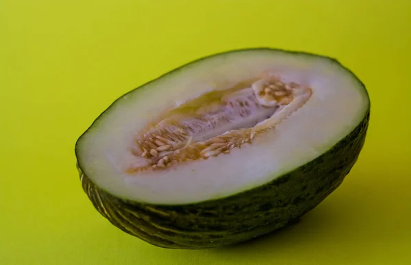 Half of the cut ripe melon with seeds on one-ton green background. Useful fruit. Summer. Season. Vitamins.