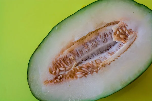 Half of the cut ripe melon with seeds on one-ton green background. Useful fruit. Summer. Season. Vitamins.