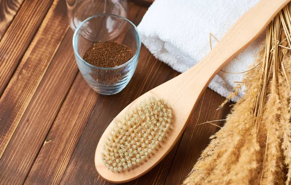 Brush, washcloth for body massage and skin cleaning with natural coffee scrub on beige background. Spa.